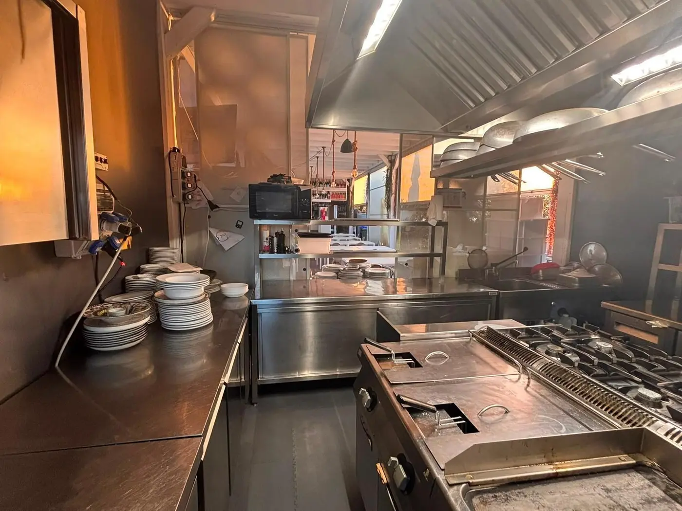 Cucina professionale di un ristorante con fuochi, friggitrici e banchi in acciaio sgrassati da VaporChic Cucina professionale di un ristorante con fuochi, friggitrici e banchi in acciaio sgrassati da VaporChic
