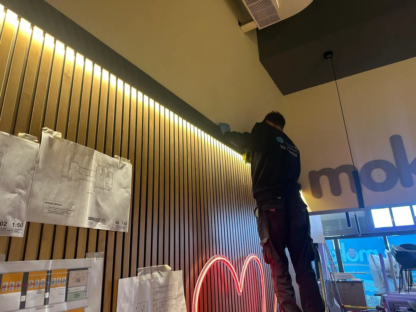 Operatore VaporChic pulisce pareti e luci di un locale Operatore VaporChic pulisce pareti e luci di un locale