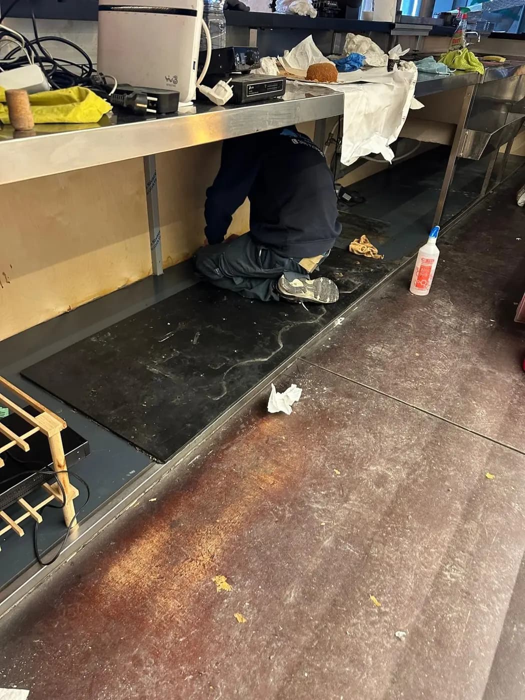 Operatore VaporChic pulisce sotto i banchi di lavoro di un locale Operatore VaporChic pulisce sotto i banchi di lavoro di un locale
