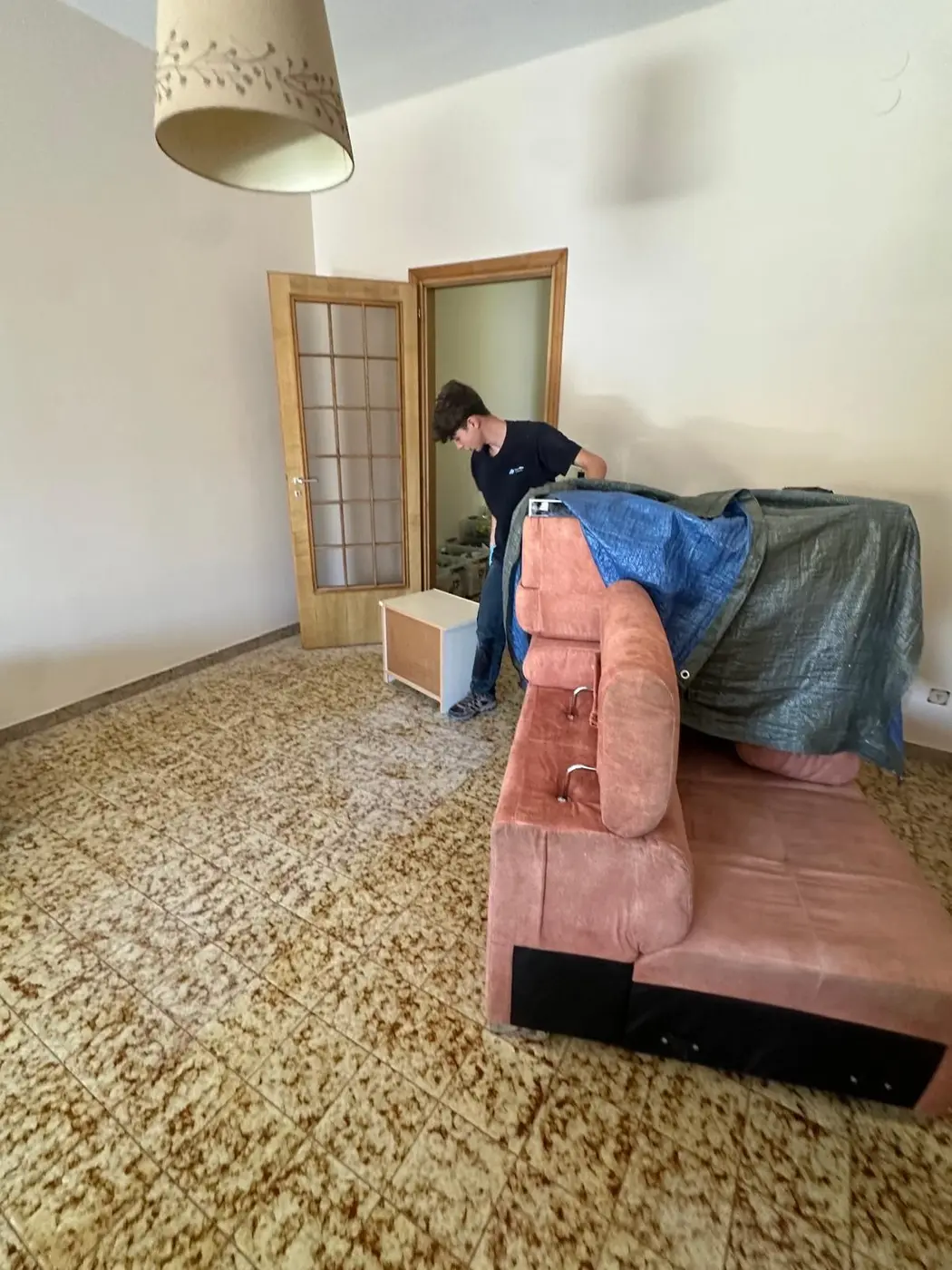 Pulizia straordinaria del soggiorno di un appartamento con il divano protetto Pulizia straordinaria del soggiorno di un appartamento con il divano protetto