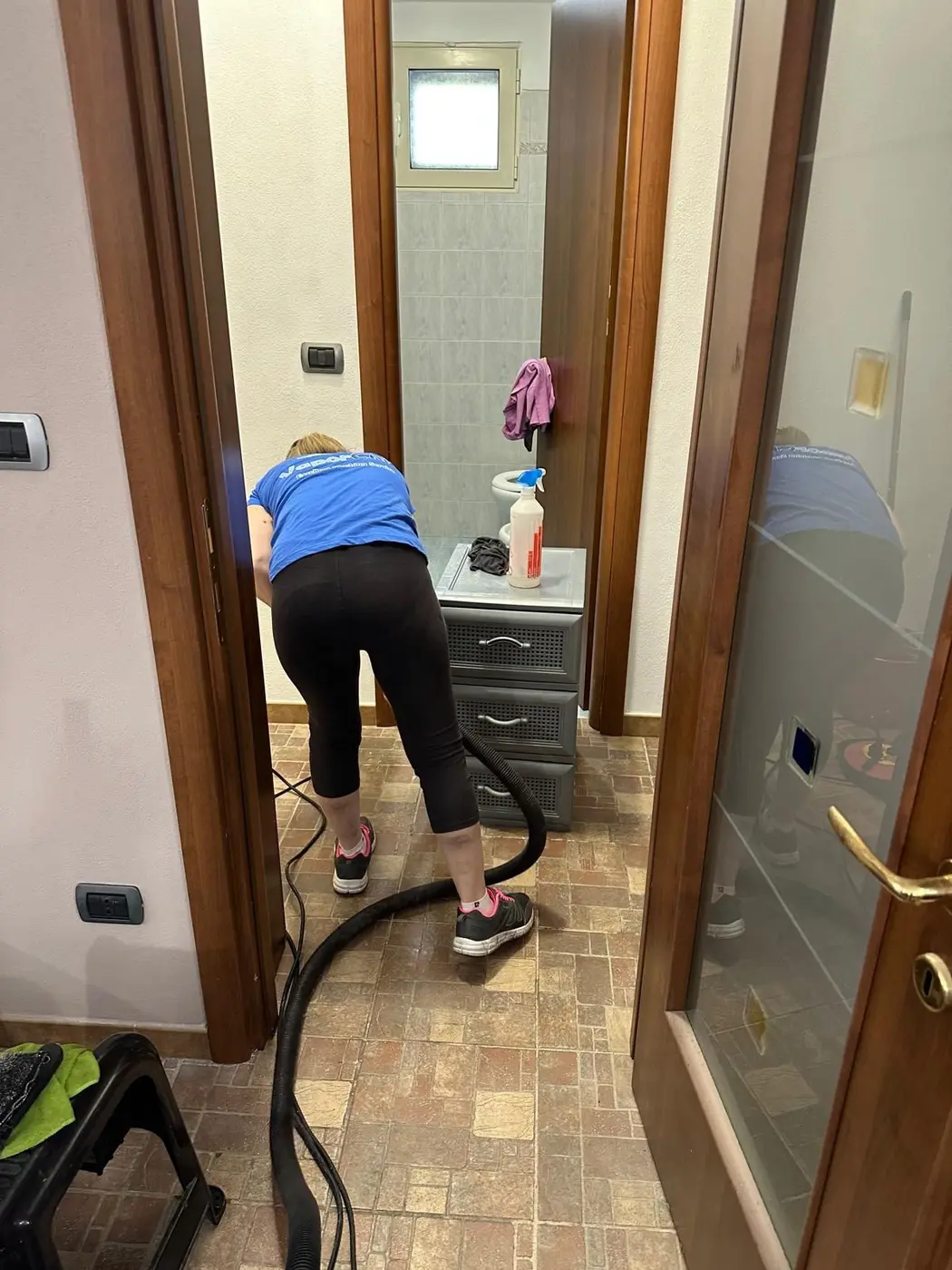 Operatrice in divisa VaporChic al lavoro nella camera da letto durante una pulizia straordinaria Operatrice in divisa VaporChic al lavoro nella camera da letto durante una pulizia straordinaria